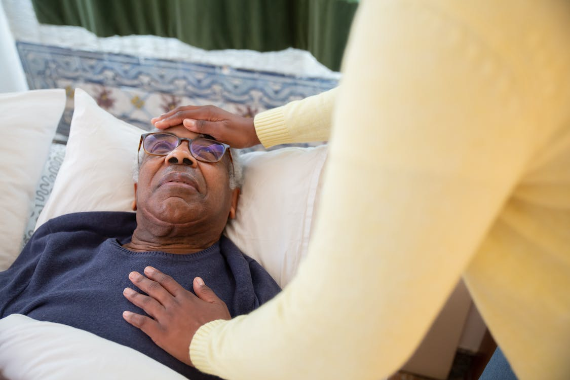 A caregiver is putting an elderly man to bed.