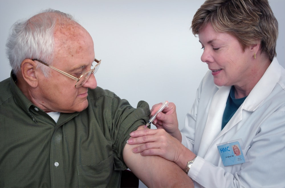 a nurse injecting a man.