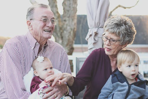 an elderly couple sitting outdoors with kids