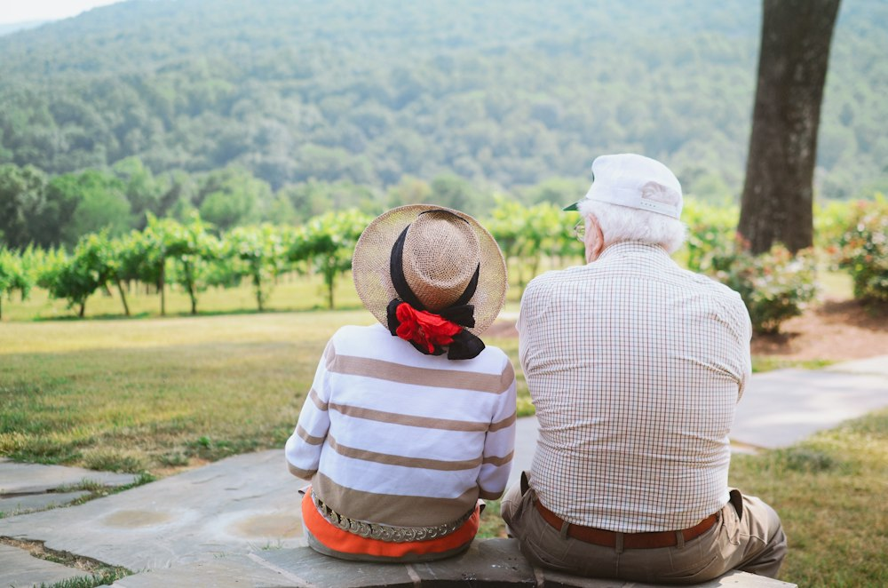 an elderly couple sitting outdoors.