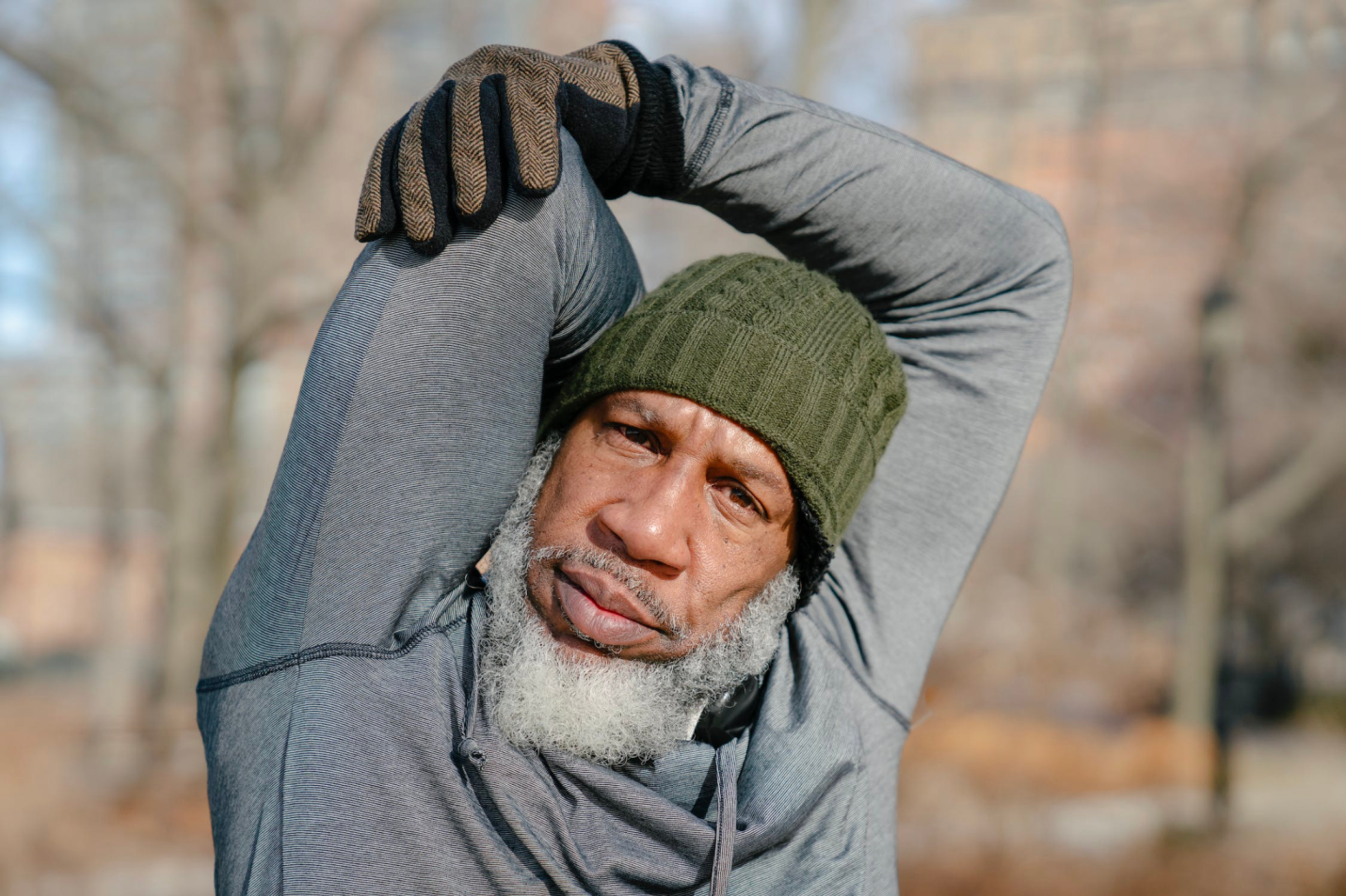 An older man stretches outdoors with structured family care.