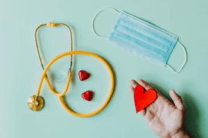 A flat-lay image of a stethoscope, mask, and hearts.