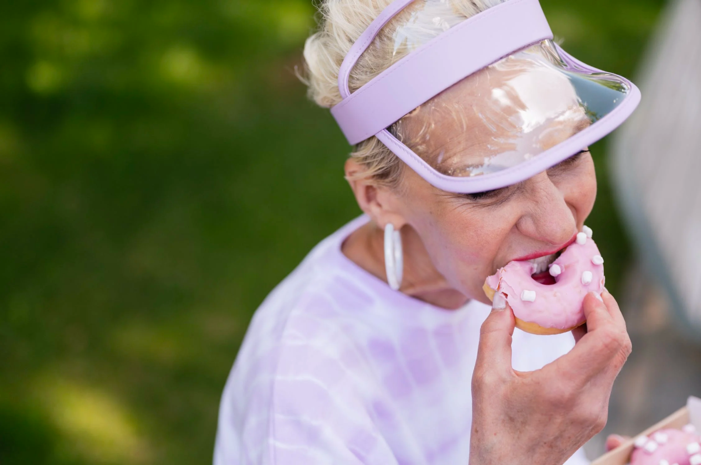 A senior enjoys a sweet treat, biting into a donut.